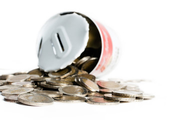 Tin canister, open, with numerous euro coins, fallen around it. Concept of spending the savings.