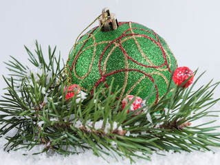 Green Christmas ball and spruce branches in the snow