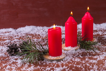 Cones, fir branches and a candle on a wooden background.