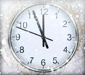 Clock on snow under decorated christmas tree