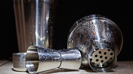 Coctelera de aluminio mojada con gotas de agua sobre un fondo negro con luz directa sobre ella