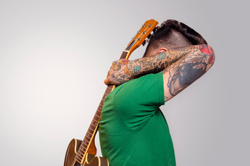 Artistic portrait Tattooed rocker male, holding guitar on his back 