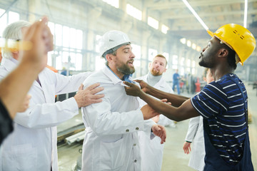 Waist up portrait of angry factory workers fighting with managers during protest in industrial...