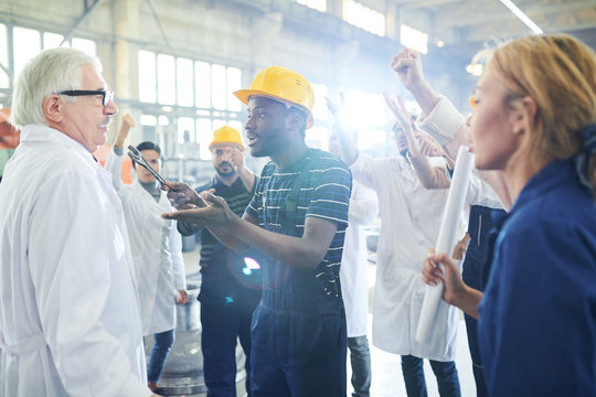 Portrait Of Angry Factory Worker Talking To Mature Manager During Strike On Industrial Plant, Copy Space