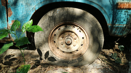 old flat tyre of old blue vehicle in the abandoned place