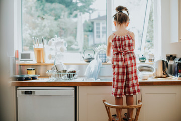 Little girl doing the dishes - obrazy, fototapety, plakaty