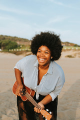 Obraz premium African American musician playing ukulele at the beach