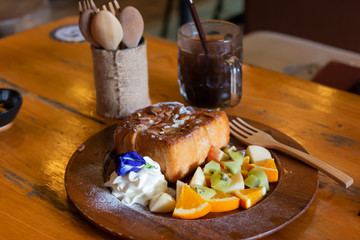 Honey toast Topped with condensed milk with Mixed Fruit on wood table
