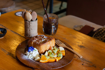 Honey toast Topped with condensed milk with Mixed Fruit on wood table
