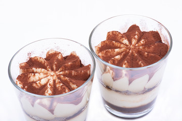 Sweet Italian dessert tiramasu with delicate mascarpone cream from traditional recipe in glass isolated on white background