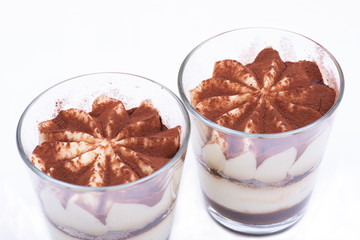 Sweet Italian dessert tiramasu with delicate mascarpone cream from traditional recipe in glass isolated on white background