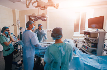 Process of gynecological surgery operation using laparoscopic equipment. Group of surgeons in...