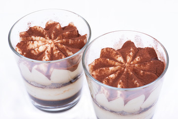 Sweet Italian dessert tiramasu with delicate mascarpone cream from traditional recipe in glass isolated on white background