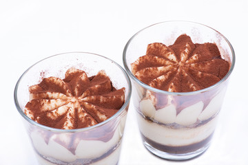 Sweet Italian dessert tiramasu with delicate mascarpone cream from traditional recipe in glass isolated on white background
