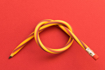 Flexible pencil . Isolated red background