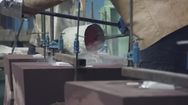 Workers in a foundry pouring liquid Aluminum to a sand cast