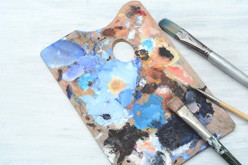Artist's palette with colorful oil paint strokes and paintbrushes