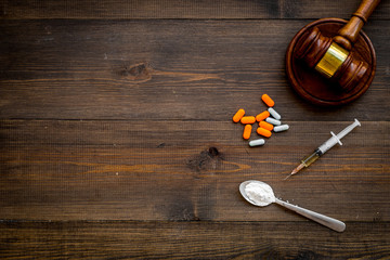 Drugs addiction, arrest for drugs. Pills, spoon with powder, syringe on dark wooden background top...