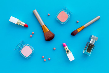 Set of pink cosmetics. Lipstick, bulk, eyeshadow, perfume near brushes on blue background top view