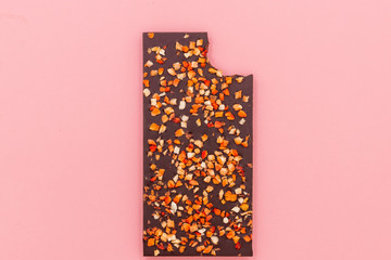 Chocolate bar with dried strawberry on a pink abstract background.