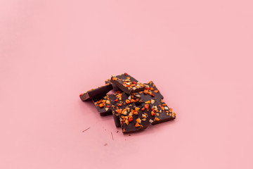 Chocolate bar with dried strawberry on a pink abstract background.