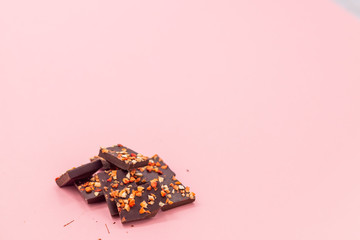 Chocolate bar with dried strawberry on a pink abstract background.
