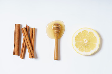 lemon, honey and cinnamon sticks on white background