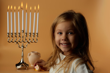 joyful girl on menorah background, candles candles on menorah, isolated on yellow, hannuka holiday...