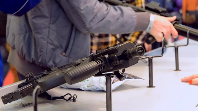 Weapon optics sight of sniper rifle with man close-up in store or shop. Firearms gun submachine sniper rifle large-caliber weapons close-up.