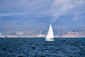 Fototapeta premium Sailboat close to the Pacific Ocean coastline near Moss Landing, Monterey Bay, California