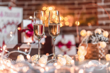 Two champagne glasses in front of christmas presents