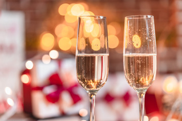 Two champagne glasses in front of christmas presents