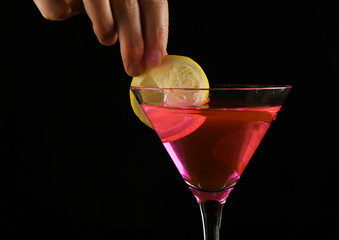 woman's hands prepares a pink cocktail with lemon in a dark. party concept