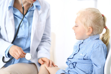 Doctor examining a little blonde girl with stethoscope.Medicine and healthcare concept