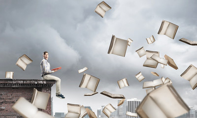 Man reading book and many of them flying in air