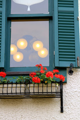 Red flowers decorated on the window side with green louvers