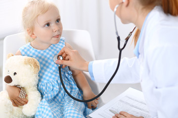 Doctor examining a little blonde girl with stethoscope.Medicine and healthcare concept