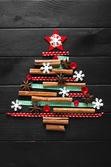 Fototapeta na wymiar Tree made of christmas decoration on wooden dark background