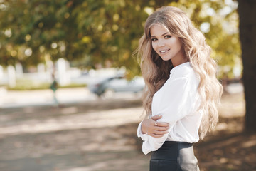 Portrait of a beautiful woman with curly hair outdoors in a spring park.Portrait dreamy and air attractive girl being playful and carefree with beautiful smile on sunny day. Healthy outdoors lifestyle