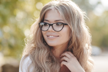 Portrait of a beautiful woman with curly hair outdoors in a spring park.Portrait dreamy and air attractive girl being playful and carefree with beautiful smile on sunny day. Healthy outdoors lifestyle