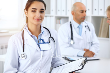 Fototapeta premium Portrait of young doctor woman in hospital. Hispanic or latin american staff in medicine