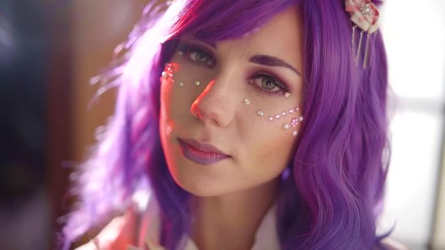 close-up of face of unusual creative girl with violet hair, woman is turning head
