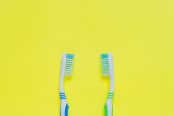 Two toothbrushes  on yellow background. Top view, minimal flat lay.
