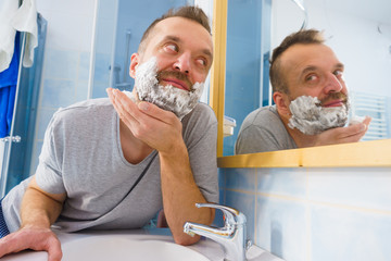 Guy shaving his beard in bathroom