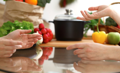 Closeup of human hands discussing something while cooking in kitchen. Women talking about menu. Family dinner, friendship and lifestyle concept
