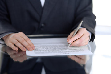 Close-up of female hands with pen over document,  business concept. Lawyer or business woman at work in office