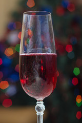 Red sparkling wine on blurred background of christmas lights
