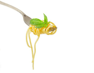 Cooked spaghetti twisted around fork and basil liaves