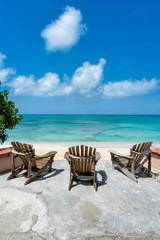 Wooden beach chairs in front of tropical ocean