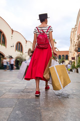 Obraz premium Young woman with shopping bags walking along city street 